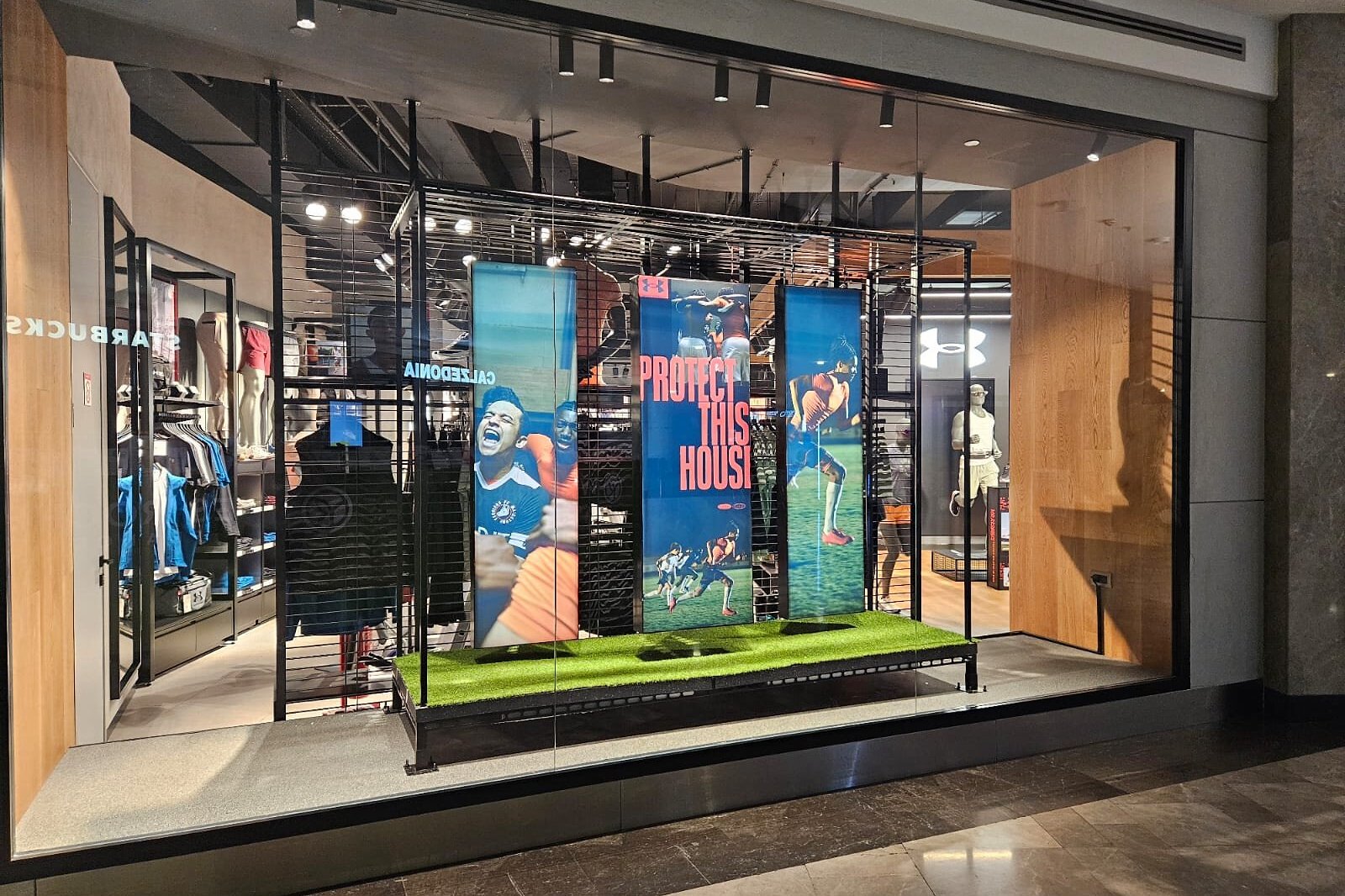Under Armour vitrin uygulaması · üç LED panel ve suni çim platform